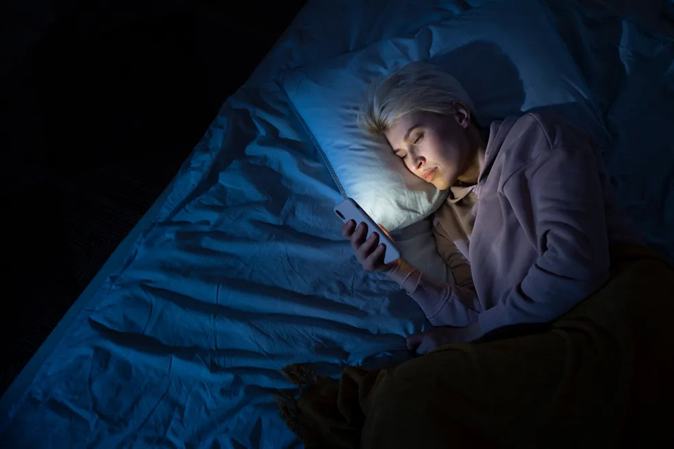 Woman awake late at night, phone in hand, exhausted and looking for answers