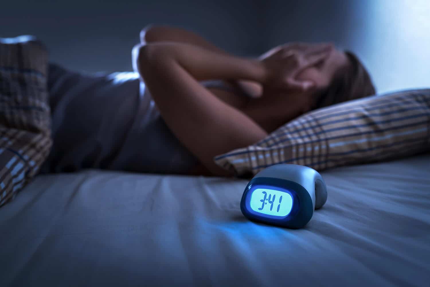 Person lying awake staring at the ceiling at 3am, unable to sleep