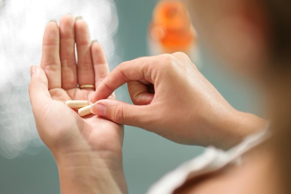 Adult taking ColonBroom GLP-1 Booster capsules with a meal